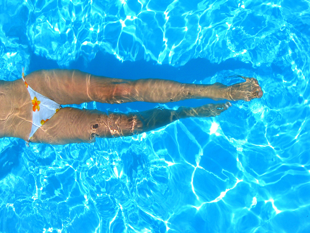 Žena leží v bazéne s vystretými nohami