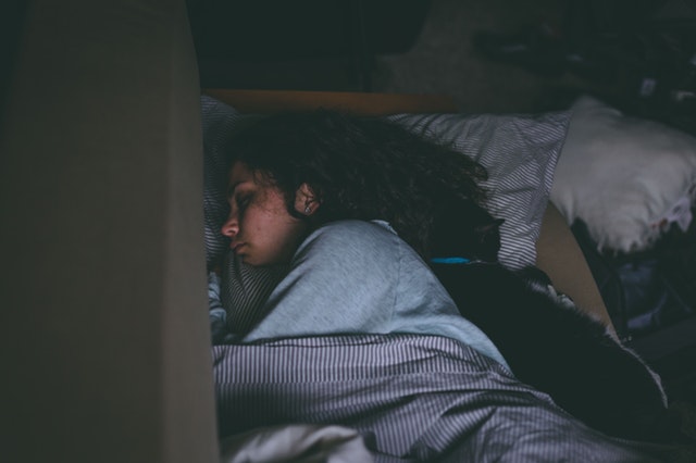 Žena s čiernymi dlhými vlasmi spí v posteli.jpg